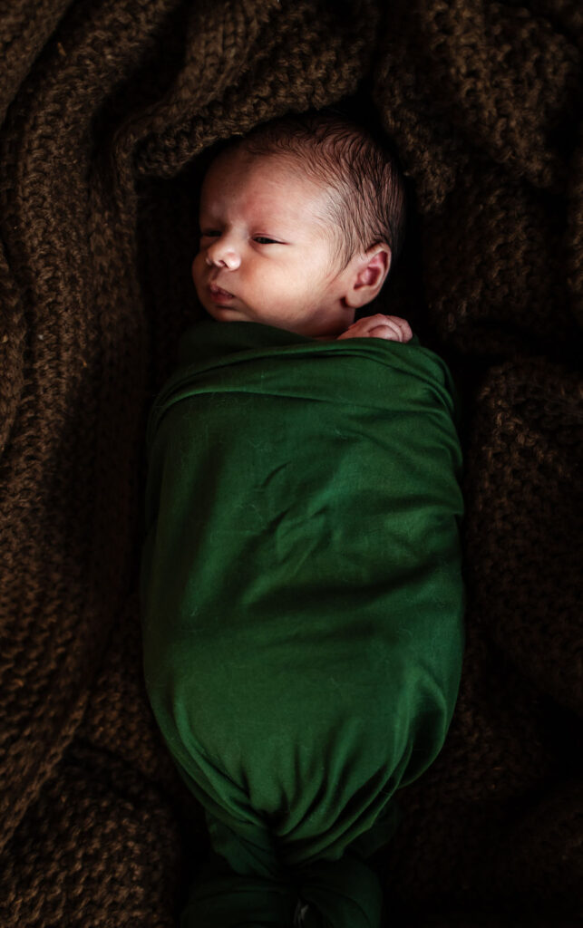 Baby boy wrapped in green newborn photo