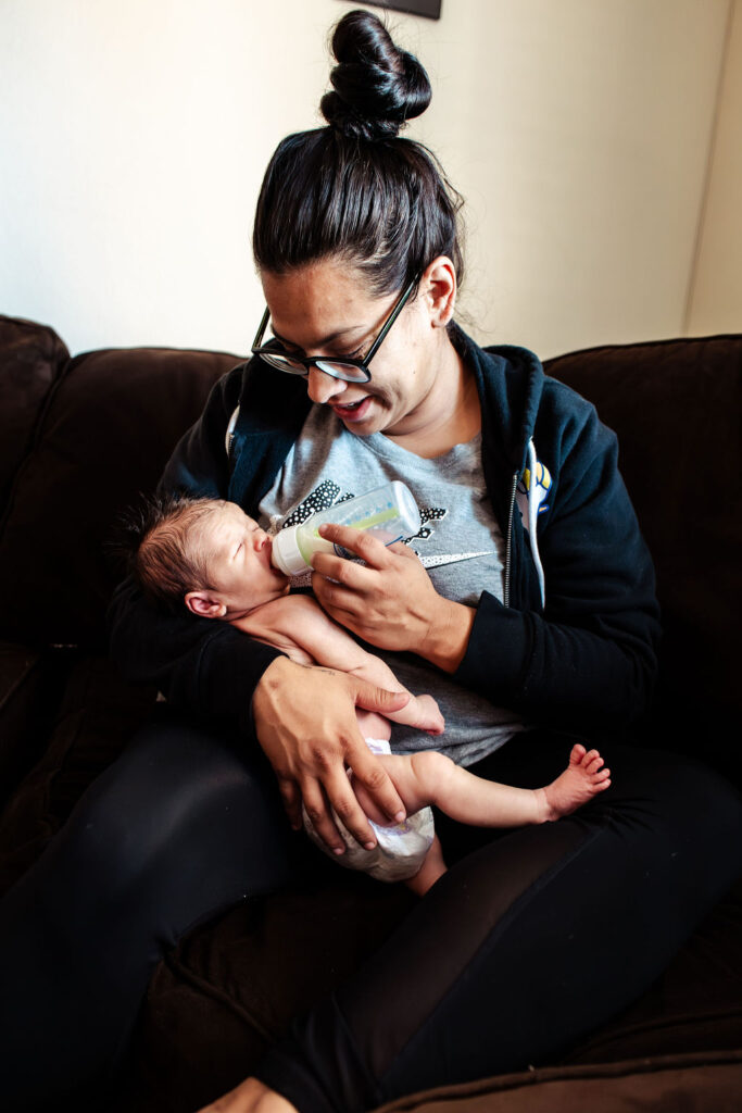 Mom feeding baby with bottle in-home newborn session
