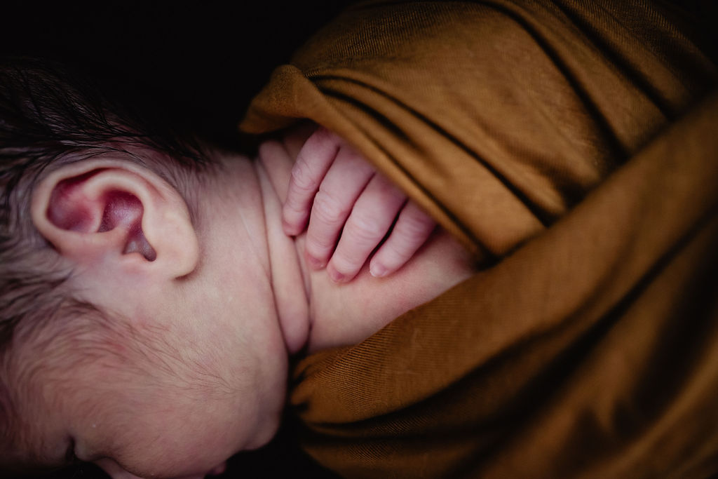 Newborn baby photoshoot baby fingers in rust wrap
