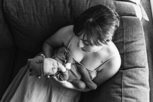 Black and white photo where mom holds new baby and looks down at him with love in her eyes