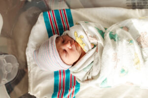 This is a newborn baby born in Modesto, California, wrapped in a hospital swaddle and sleeping. 