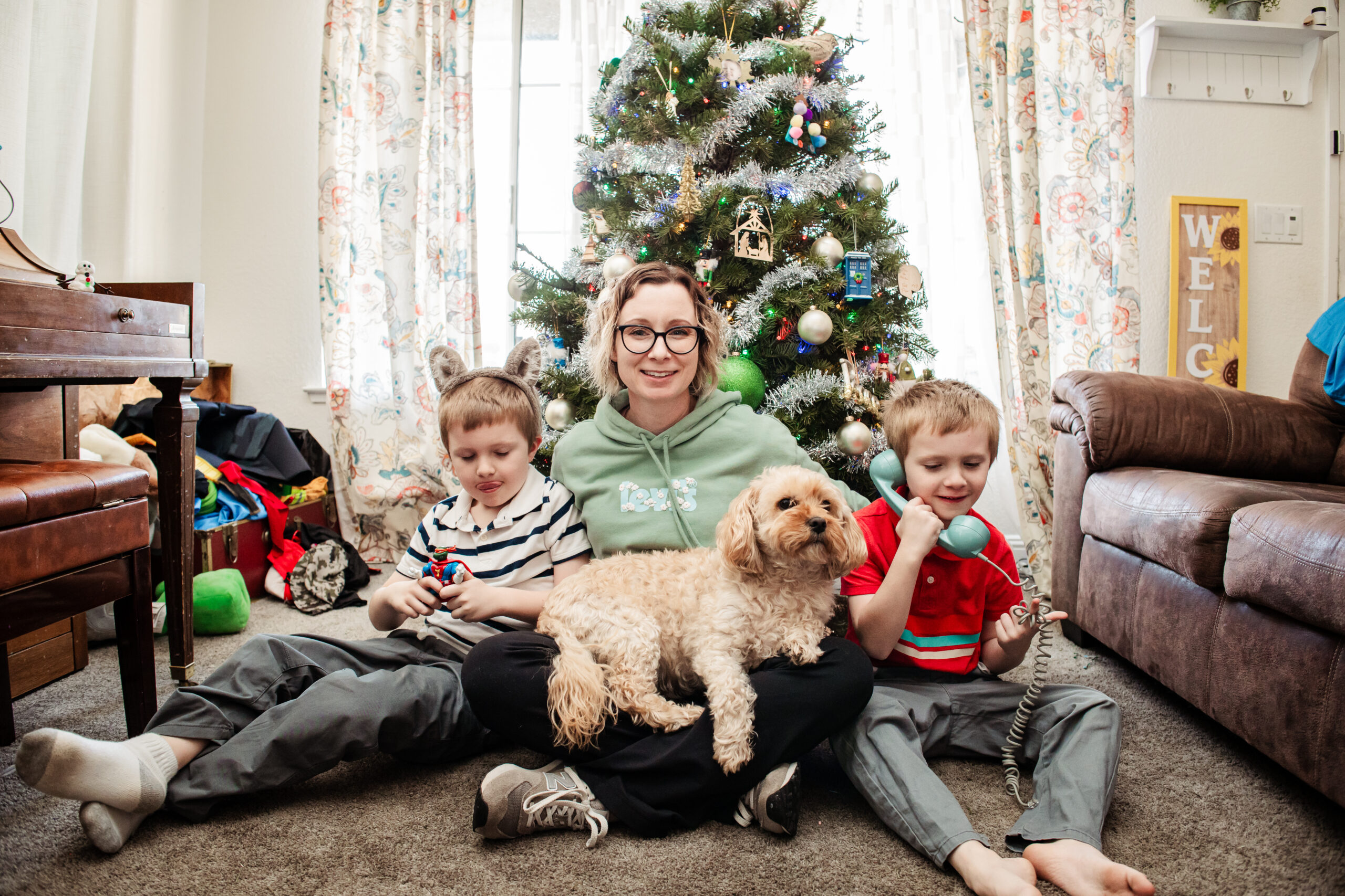 A mom sits in front of the Christmas tree with her two kids