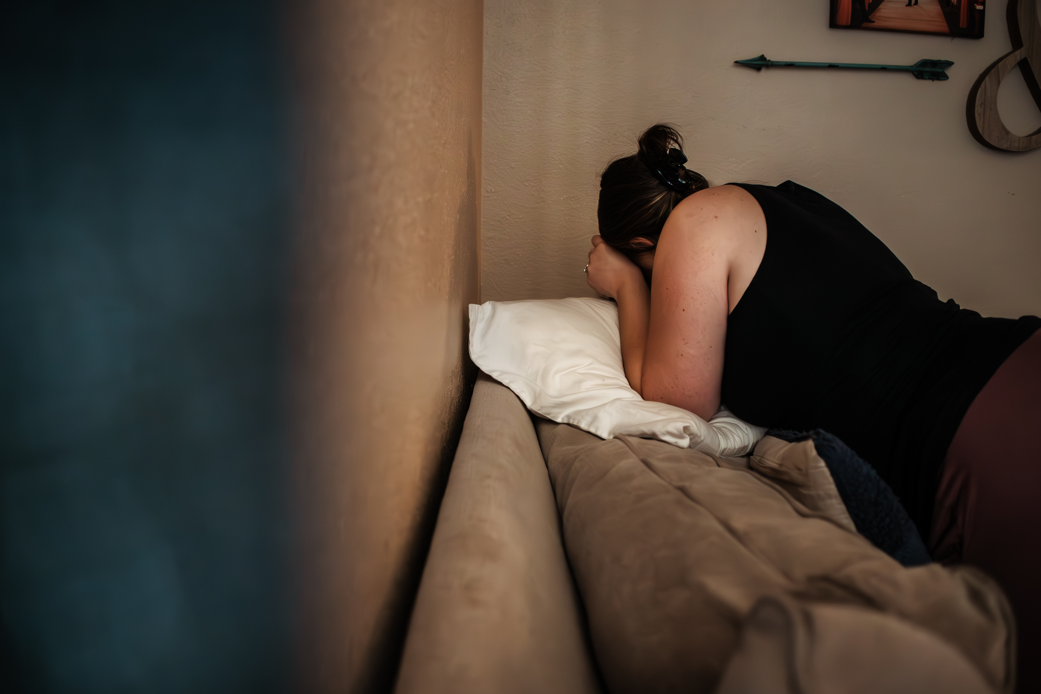 A girl in labor turns into a corner and leans on the couch during contractions